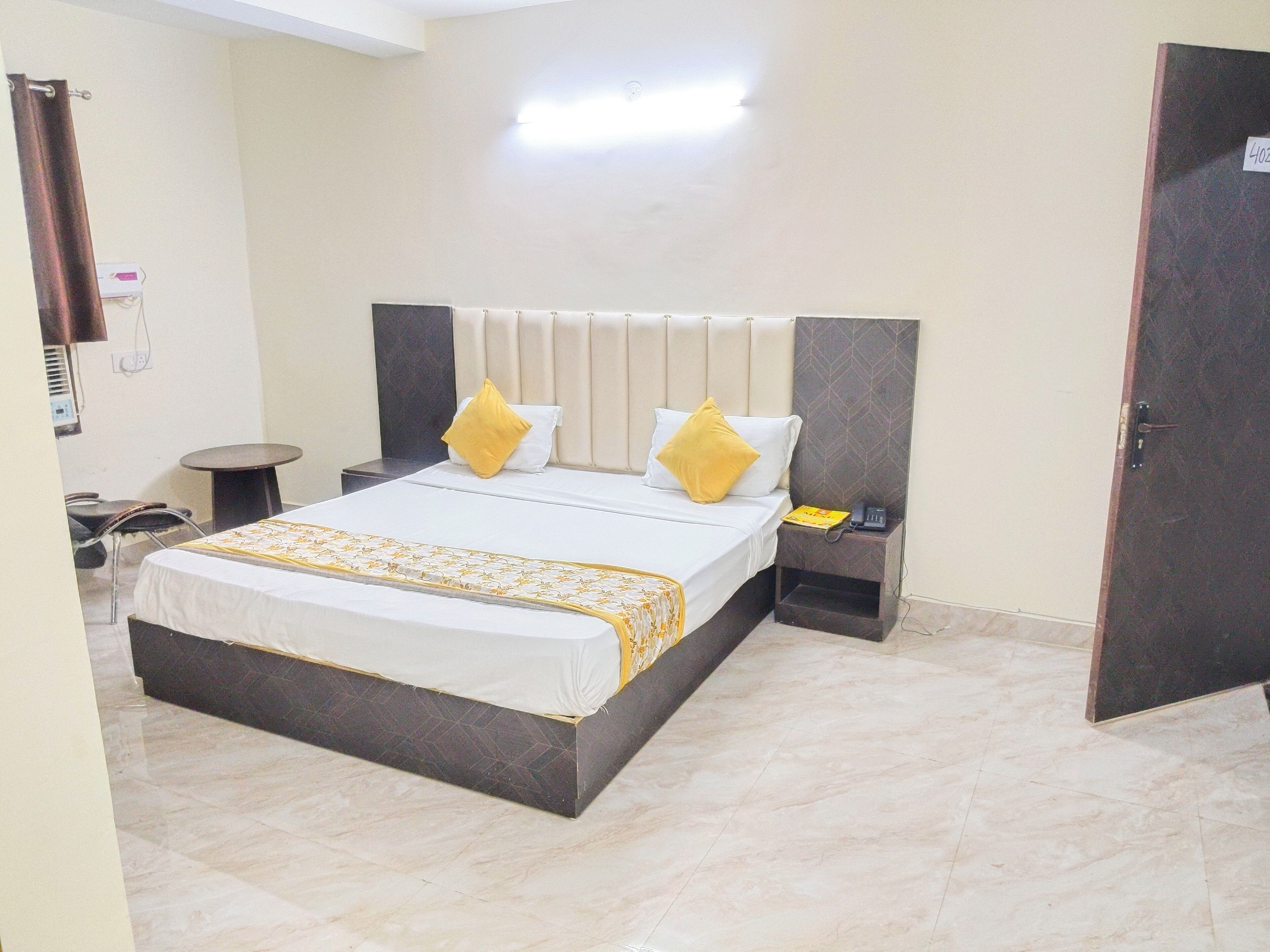 A hotel room with a large bed, two bedside tables, a chair, a small round table, and a door.
