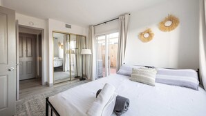 A hotel room with a bed, a mirror, and a view of the outside.