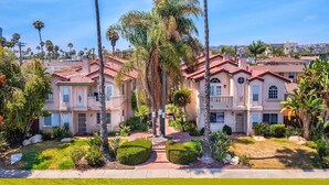 A residential area with multiple two-story houses featuring red-tiled roofs and stucco exteriors.