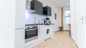 A compact kitchen with a built-in oven, microwave, and washing machine. - Chic 1BR Apt Walk to Vienna Sights (Vienna)