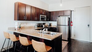 A modern kitchen with dark wooden cabinets, stainless steel appliances, and a granite countertop.