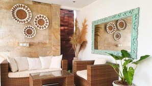 A modern living room with wicker furniture, a glass coffee table, and decorative wall art.