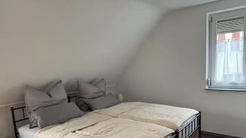 A single bed with a headboard, a bedside table, and a window with blinds.