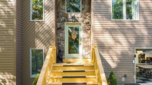 A wooden staircase leading to a stone entrance with a bear statue at the bottom.