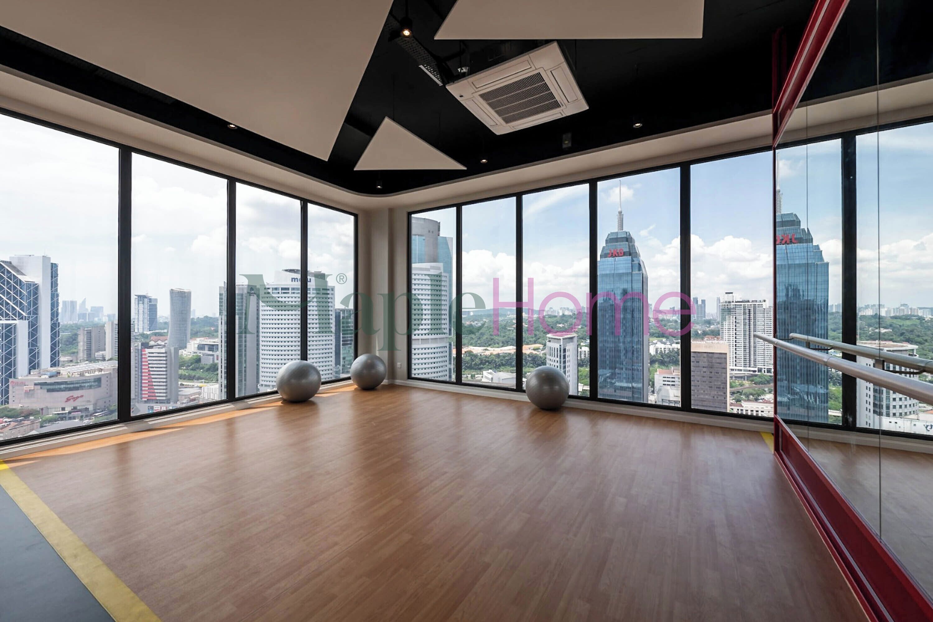 Habitación amplia con ventanas grandes que ofrecen vista a la ciudad, piso de madera y pelotas de ejercicio.