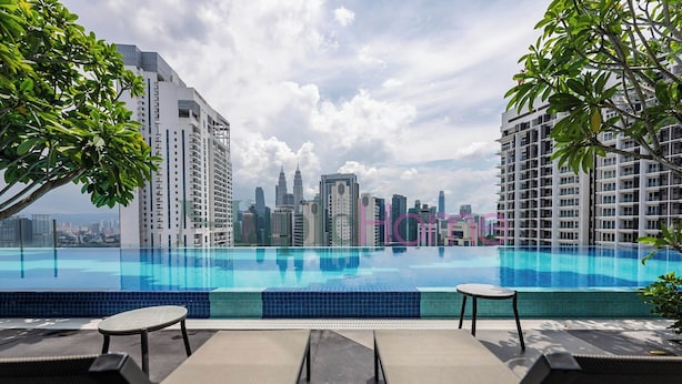 Una piscina en la azotea con sillones reclinables y vistas del horizonte urbano.