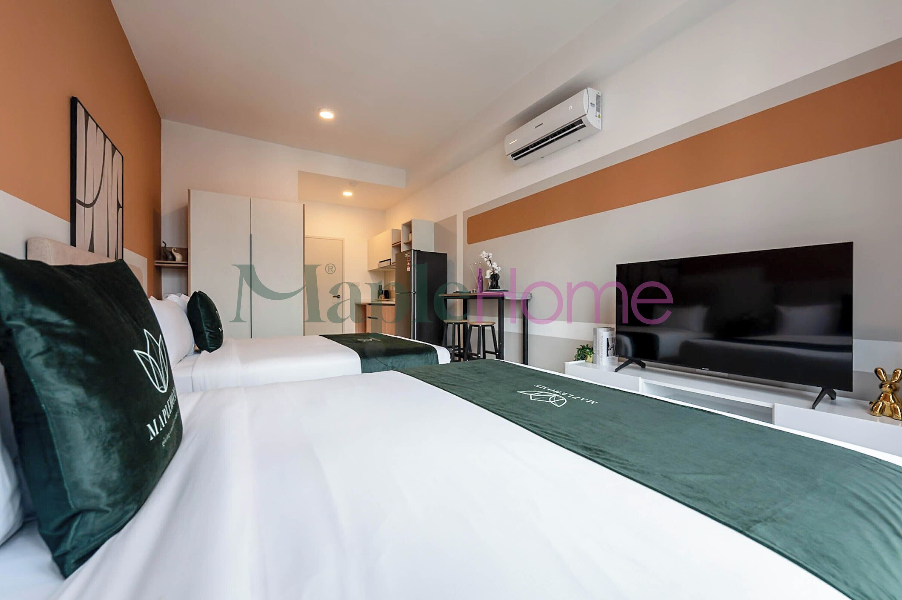 A modern hotel room with a large bed, a TV, and a kitchenette.
