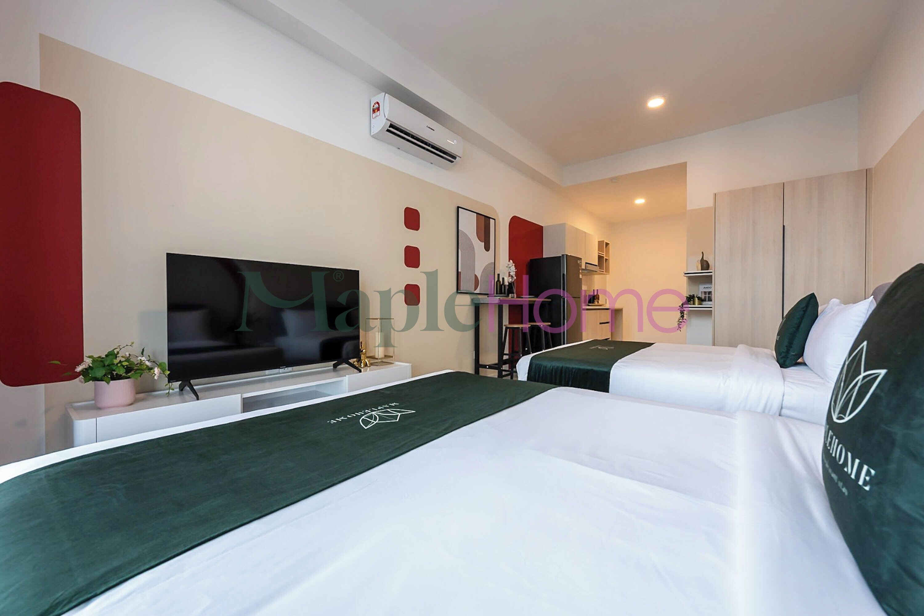 A hotel room with two beds, a flat-screen TV, a desk, and a small plant.