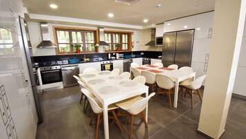 A modern kitchen with a dining area, featuring a large island, built-in appliances, and ample natural light.