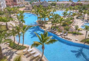 A resort with multiple swimming pools, palm trees, and lounge areas.