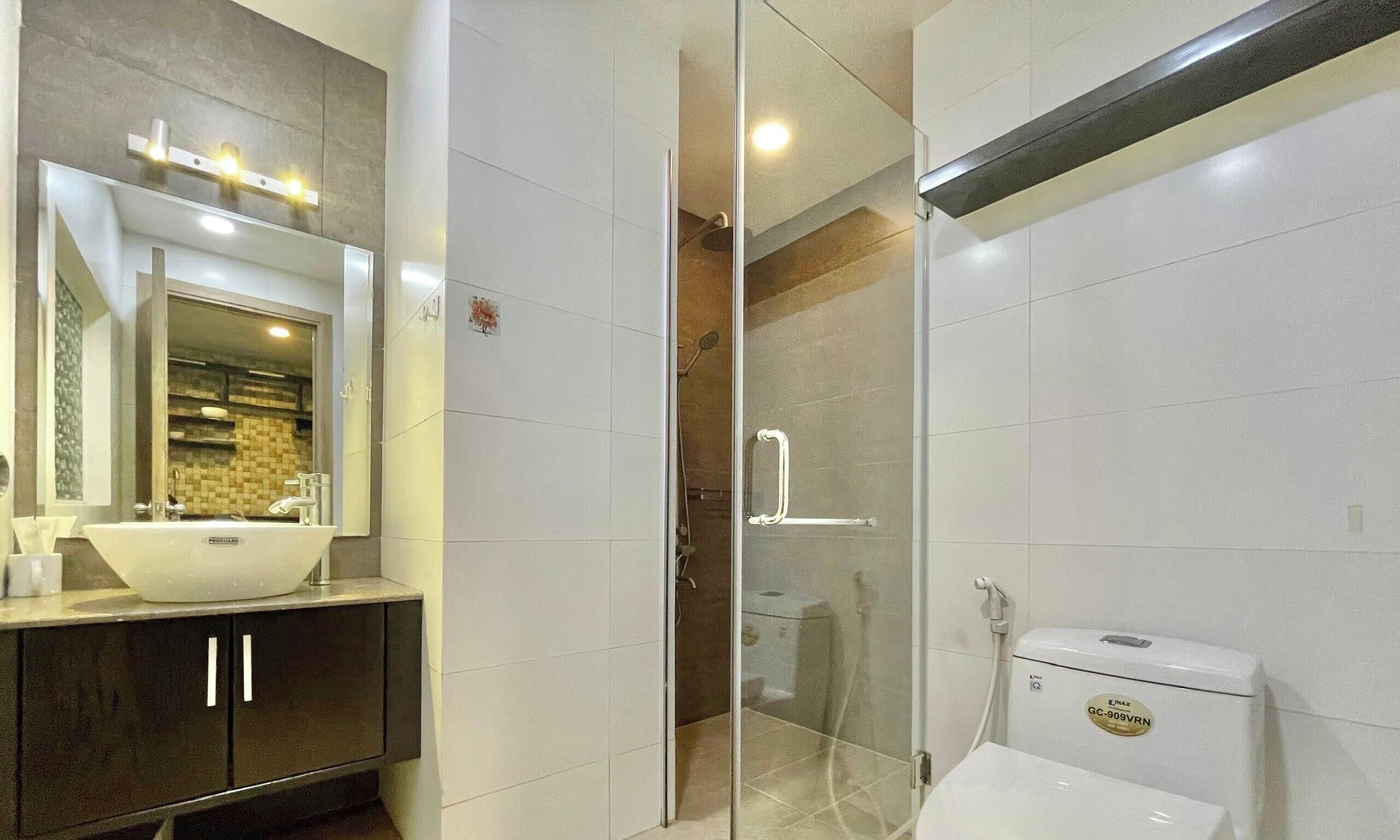 A modern bathroom with a glass-enclosed shower, a white sink, and a toilet.