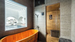 A modern bathroom with a wooden bathtub, a glass-enclosed shower, and a large window offering a view of the cityscape. - 5H - SaiGon Huch Villa by SAVIHOUSE (Ho Chi Minh City)