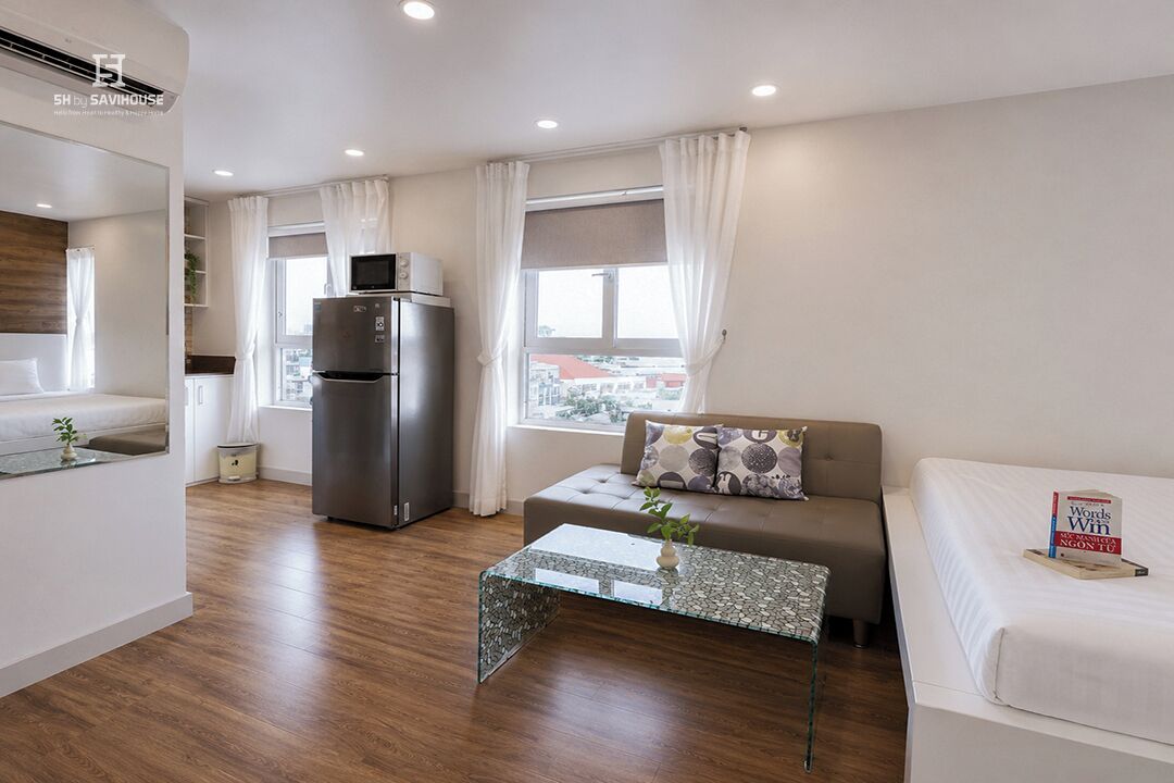 Una sala de estar moderna con un sofá, una mesa de centro, un refrigerador y una ventana con cortinas.