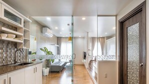 A modern kitchen with a tiled backsplash, a built-in oven, and a glass door leading to a dining area. - 5H - SaiGon Huch Villa by SAVIHOUSE (Ho Chi Minh City)