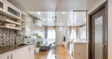 Uma cozinha moderna com painel de azulejos, forno embutido e porta de vidro que dá para uma área de refeições.
