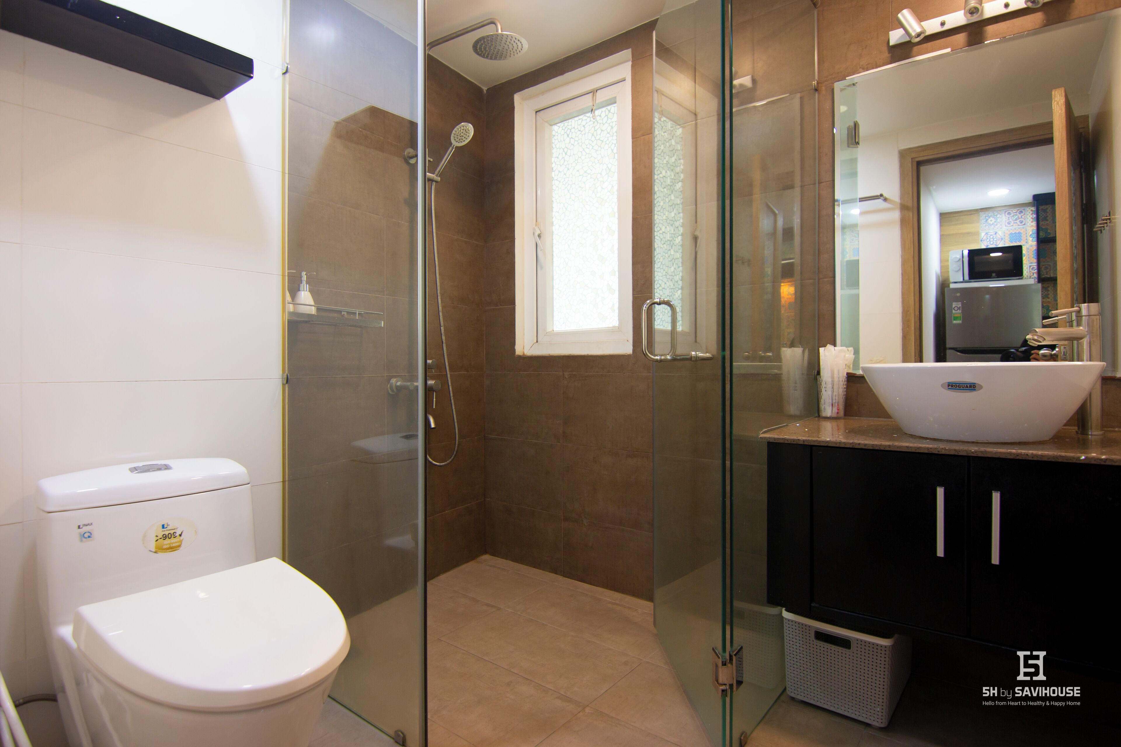 A modern bathroom with a glass-enclosed shower, a white toilet, and a black cabinet with a white sink.