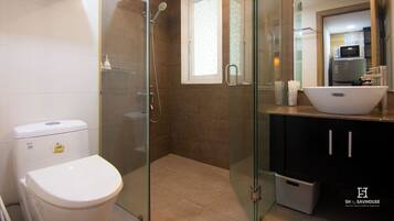 A modern bathroom with a glass-enclosed shower, a white toilet, and a black cabinet with a white sink.