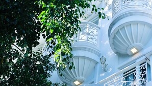 A white building with ornate balconies and a window with a decorative grille. - 5H - SaiGon Huch Villa by SAVIHOUSE (Ho Chi Minh City)