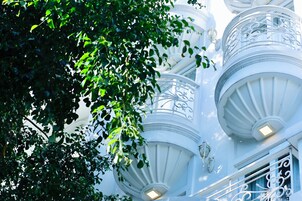 A white building with ornate balconies and a window with a decorative grille.