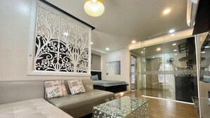 A modern living room with a sofa, decorative wall art, and a glass coffee table. - 5H - SaiGon Huch Villa by SAVIHOUSE (Ho Chi Minh City)