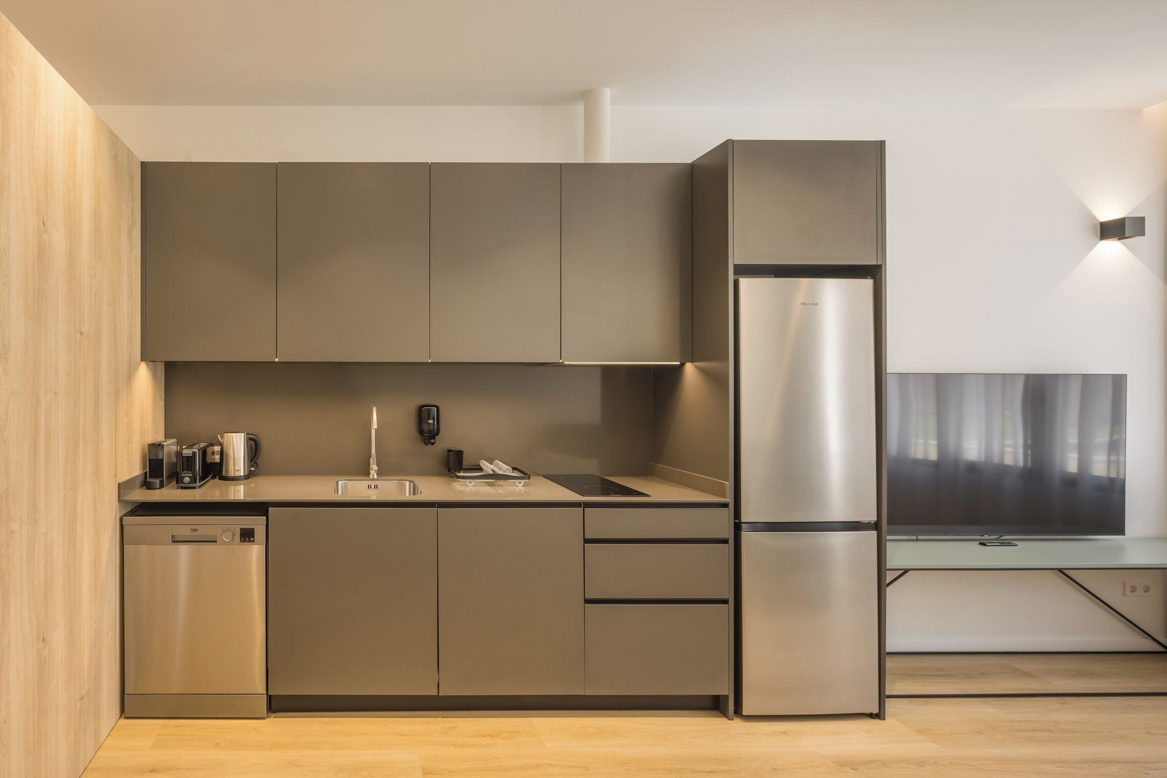 A modern kitchen with built-in appliances, a dishwasher, and a large refrigerator.