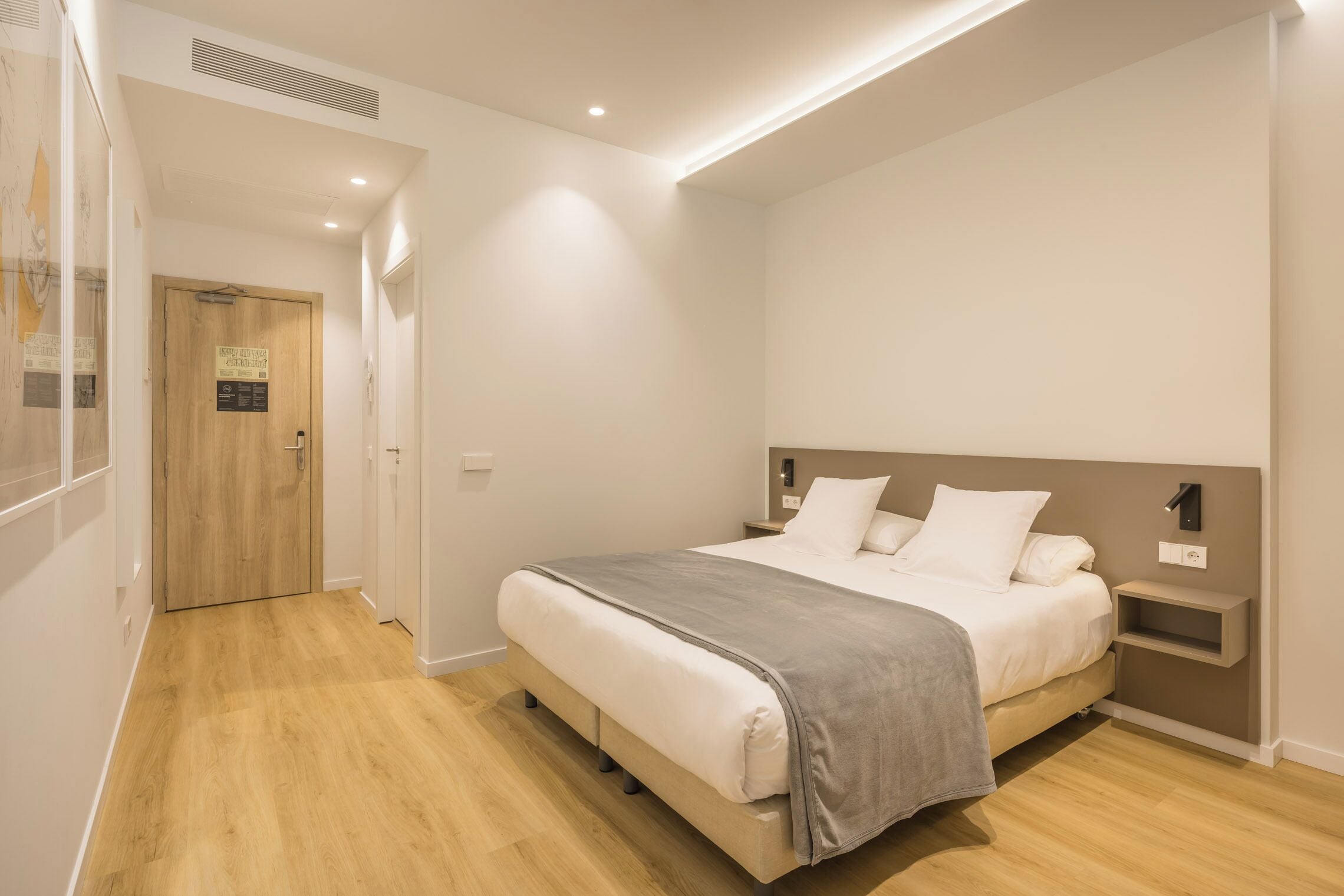 Une chambre moderne avec un grand lit, des tables de chevet et une porte en bois.