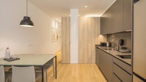 A modern kitchen with a dining area, featuring a central island, built-in appliances, and a pendant light. - Mon Suites Jardín de Ayora (València)