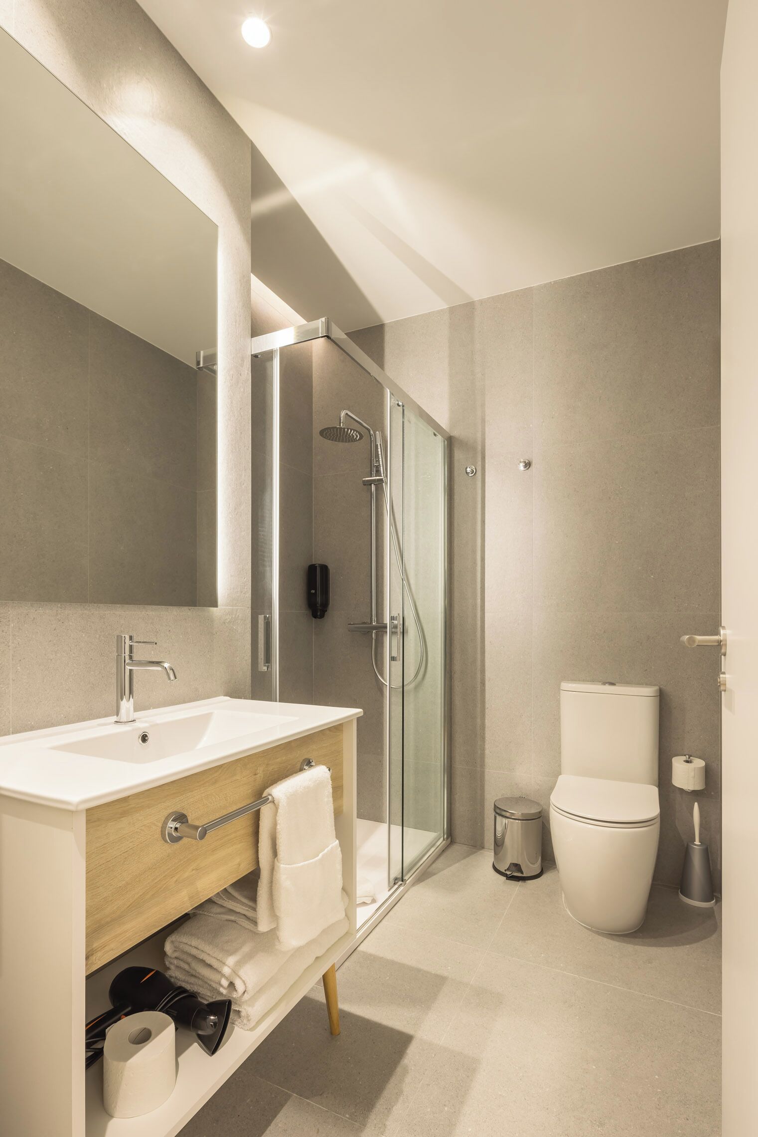 Une salle de bain moderne avec une douche à parois de verre, un lavabo blanc et des toilettes.