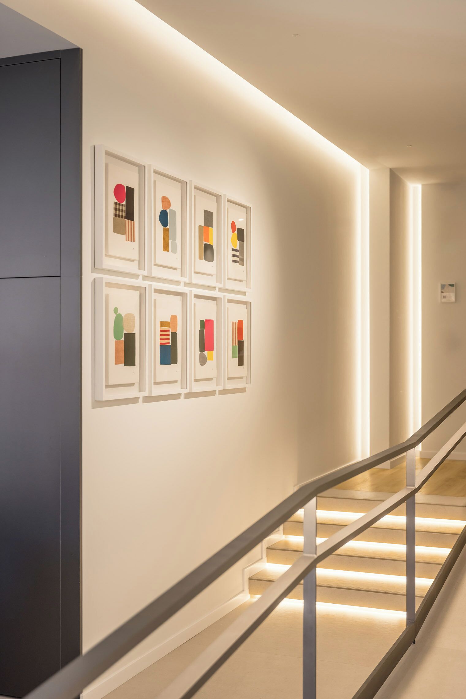 Ein modernes Interieur mit einer Treppe und gerahmten Kunstwerken an der Wand.