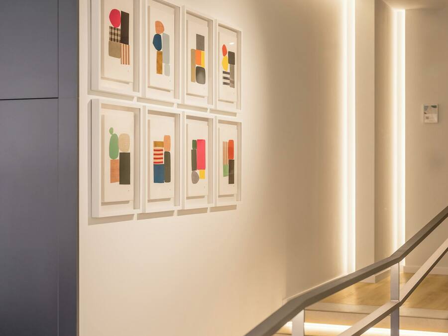 Ein modernes Interieur mit einer Treppe und gerahmten Kunstwerken an der Wand.