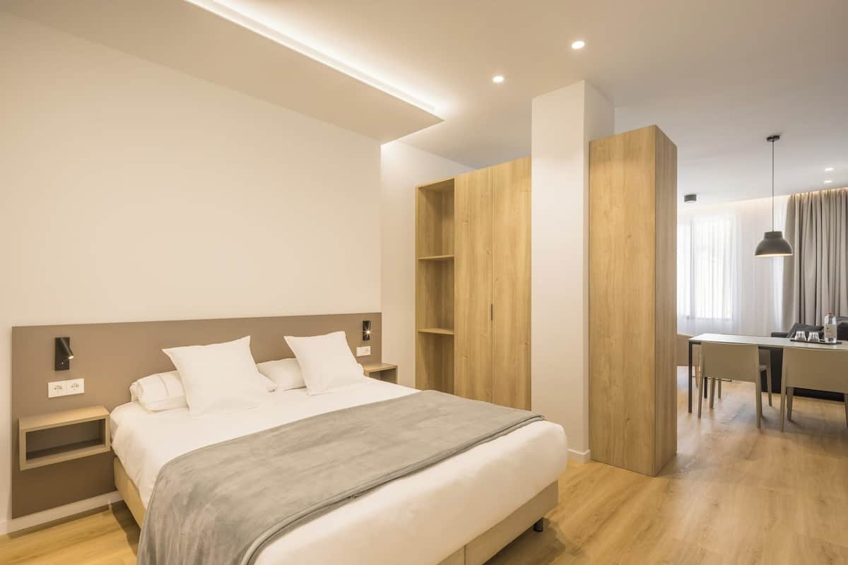 Un dormitorio moderno con una cama, mesitas de noche, un armario de madera y un escritorio con una silla.