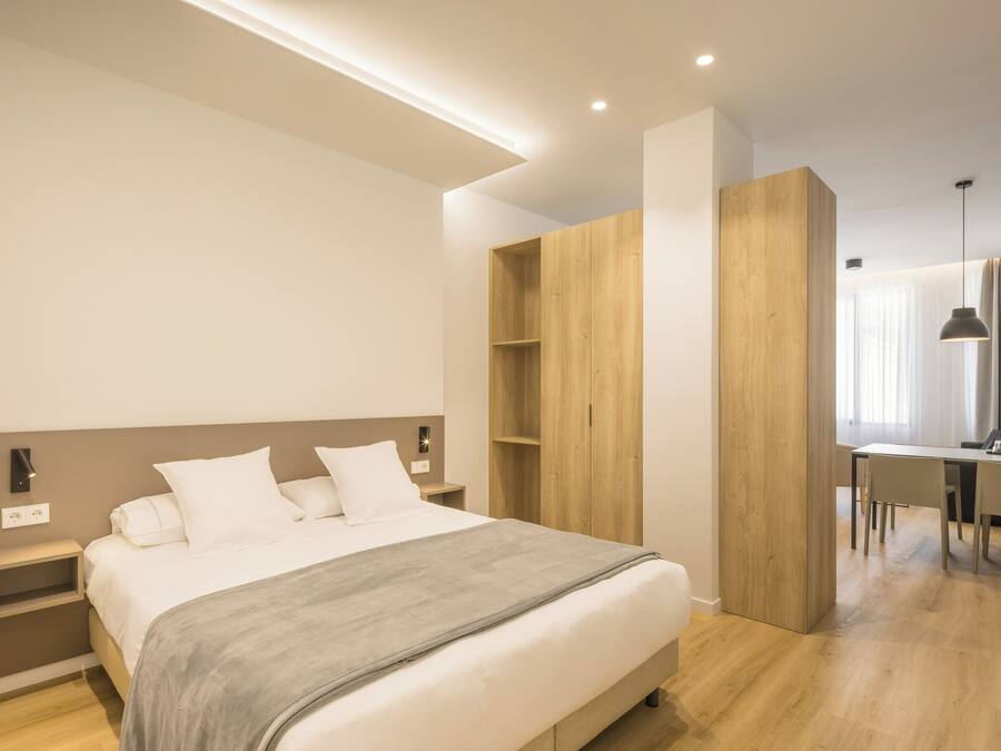 Un dormitorio moderno con una cama grande, un armario de madera y una zona de escritorio.