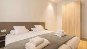 A modern hotel room with a large bed, a wooden wardrobe, and a bedside table. - Mon Suites Jardín de Ayora (València)