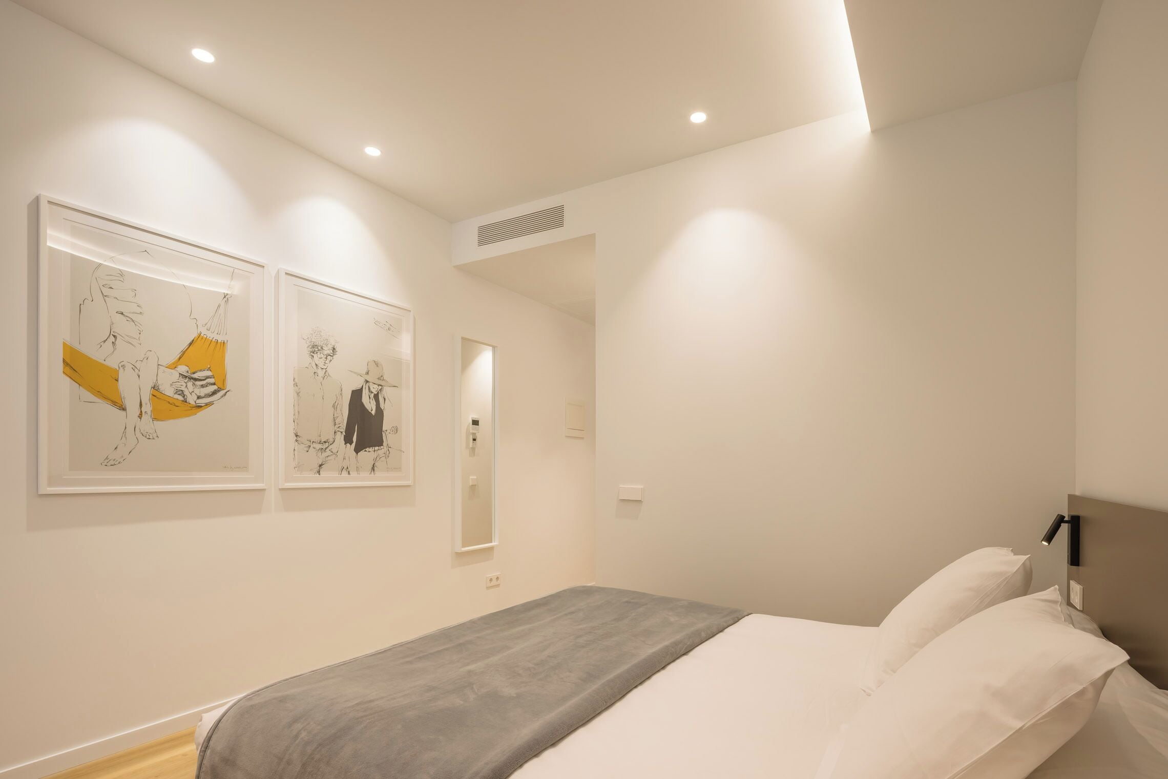 Una habitación de hotel moderna con cama, paredes blancas y una obra de arte en la pared.