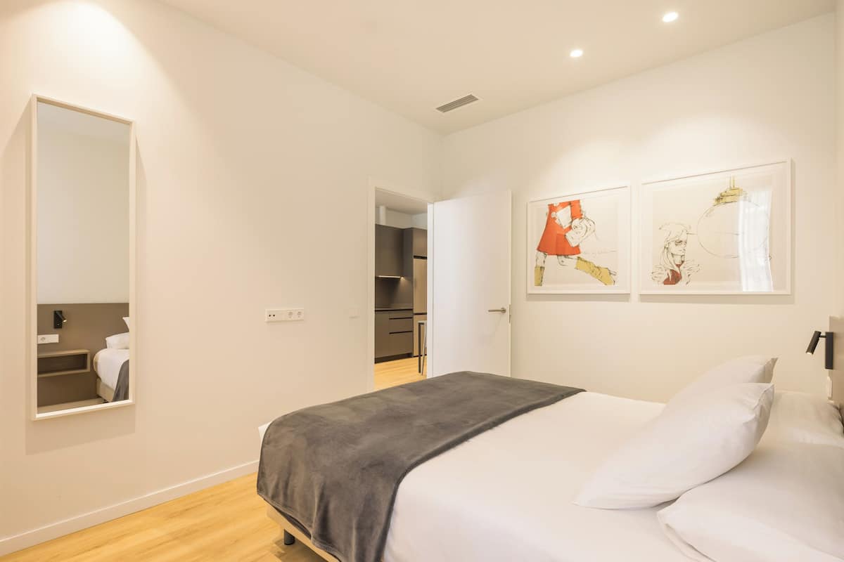 Un dormitorio moderno con una cama, un espejo y obras de arte en la pared.