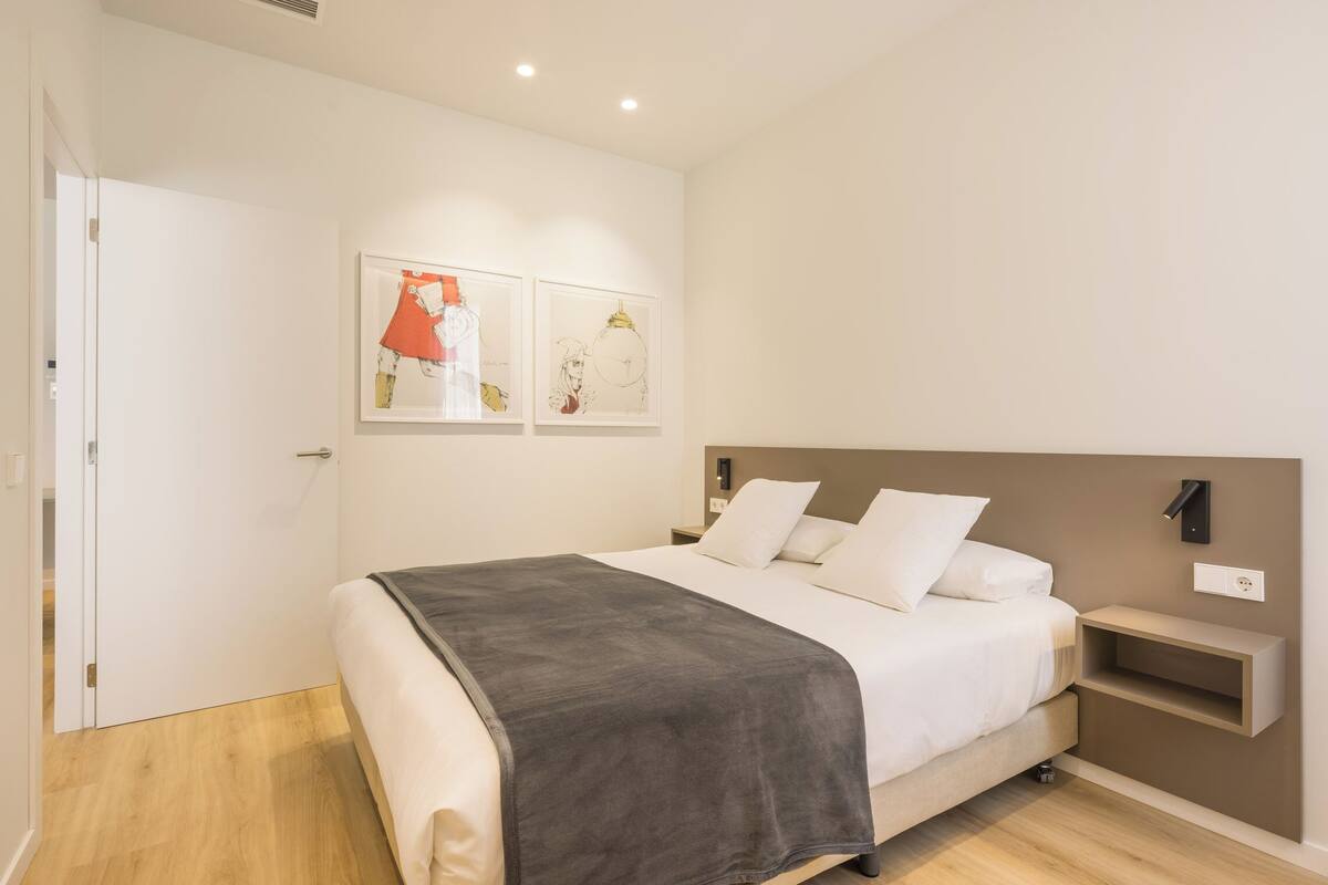 Un dormitorio moderno con una cama, una mesita de noche y dos obras de arte colgadas en la pared.