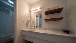 A bathroom with a white sink, a mirror, and two wooden shelves above the sink.