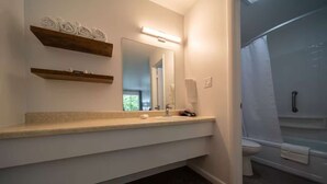 Une salle de bain moderne avec un grand miroir, un lavabo et un espace douche.