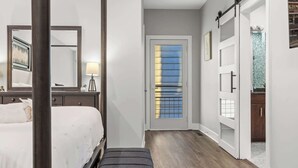 A bedroom with a bed, bedside table, lamp, and a large mirror. - NEW Elegant Downtown Escape with Modern Comforts (Louisville)