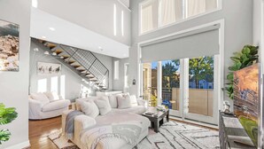 A spacious living room with a large sofa, a coffee table, and a staircase leading to an upper level. - NEW Elegant Downtown Escape with Modern Comforts (Louisville)