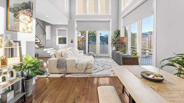 A spacious living area with a large sofa, a dining table, and a staircase leading to an upper level. - NEW Elegant Downtown Escape with Modern Comforts (Louisville)