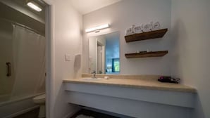 Une salle de bain avec un lavabo blanc, un miroir et deux étagères en bois au-dessus.