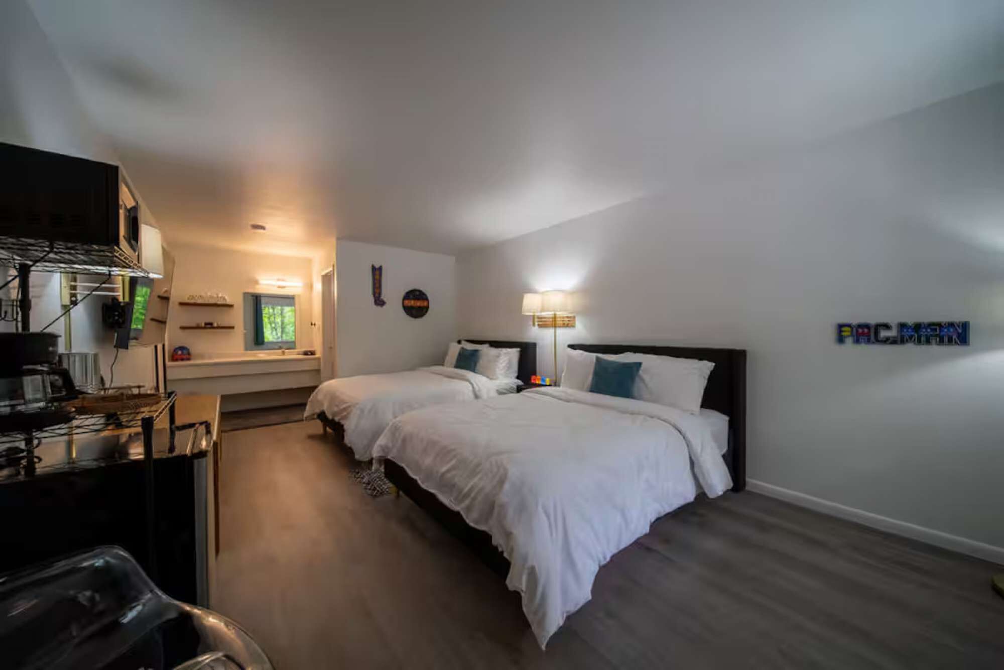 Ein Hotelzimmer mit zwei Betten, einem Schreibtisch, einem Stuhl, einem Fernseher und einer Wandlampe.