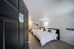 A hotel room with two beds, a nightstand, a lamp, and a sign indicating the room number. - Arcade room, #3 at Glory Dayz! (Eureka Springs)