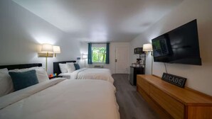 A hotel room with two beds, a TV, a desk, and a window.