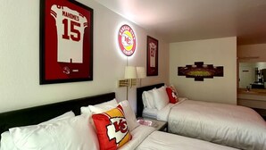 A hotel room with two beds, a framed jersey, a team logo, and a lamp. - KC Room, #7 at Glory Dayz! (Eureka Springs)
