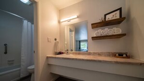 A modern bathroom with a large mirror, wooden shelves, and a shower area. - Galaxy Room, #9 at Glory Dayz! (Eureka Springs)