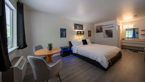 A modern hotel room with a bed, a desk, a chair, and a small table. - Galaxy Room, #9 at Glory Dayz! (Eureka Springs)