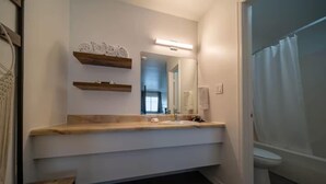 Ein Badezimmer mit einem Holzbadschränken, einem großen Spiegel und einer Duschvorhang.
