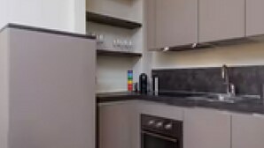 Una cocina moderna con gabinetes grises, una encimera negra y un horno empotrado.